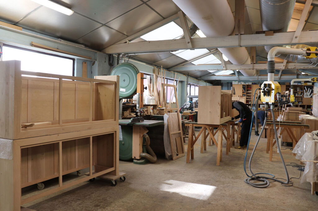 Atelier de fabrication de meubles avec machines, outils et meubles en bois en construction.